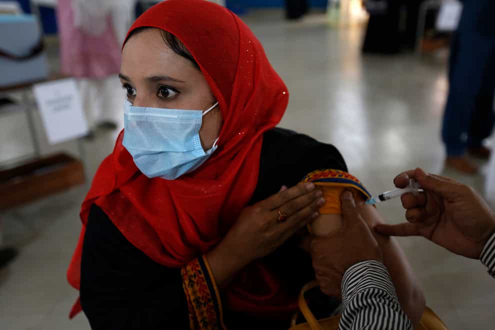 A teacher receives the first shot the Sinovac coronavirus vaccine from a paramedic in a vaccination centre at a school, in Lahore, Pakistan (K.M. Chaudary/AP)