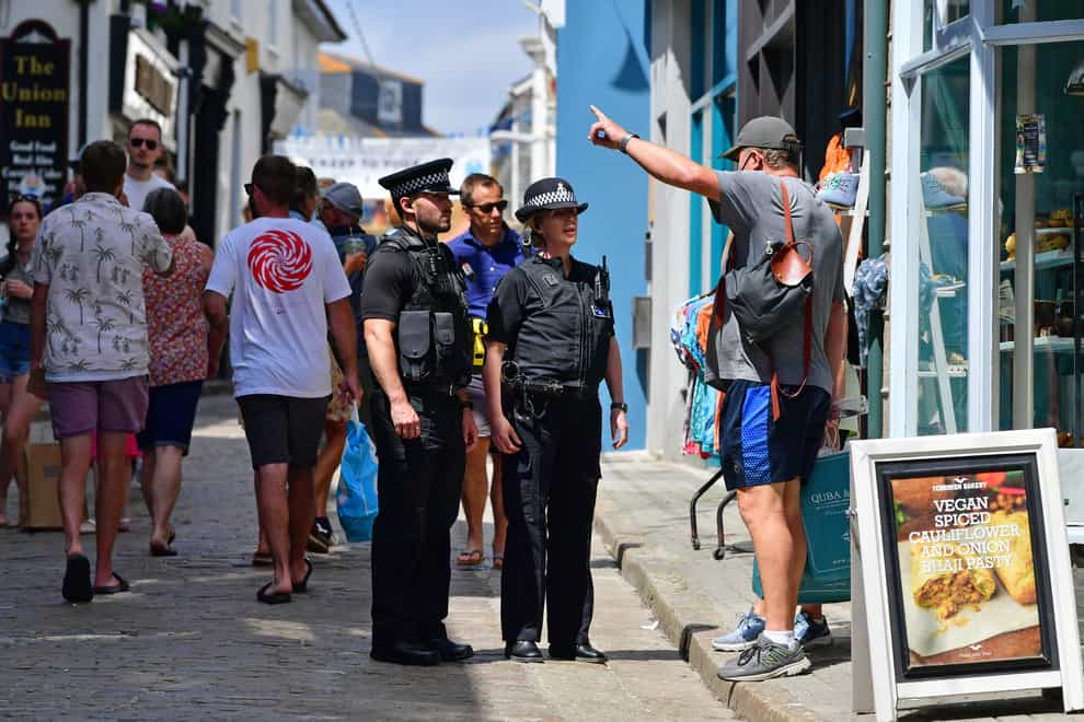 <p>Police officers speak to a member of the public in St Ives</p>