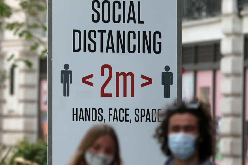 <p>Two people wearing masks in front of a social distancing sign in Regent Street, London</p>