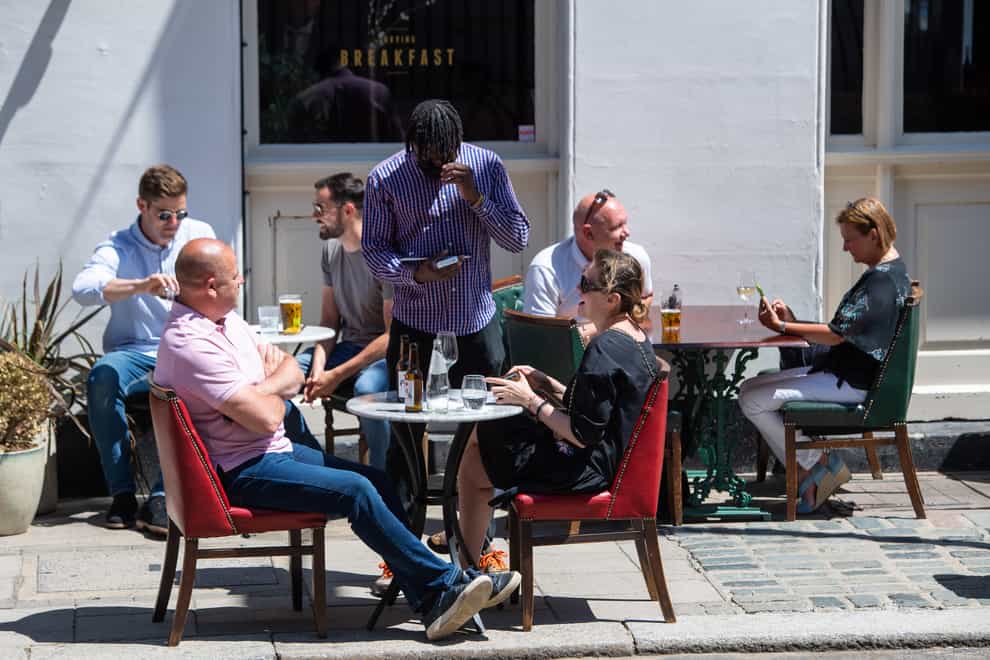 People eat and drink at tables outside a pub