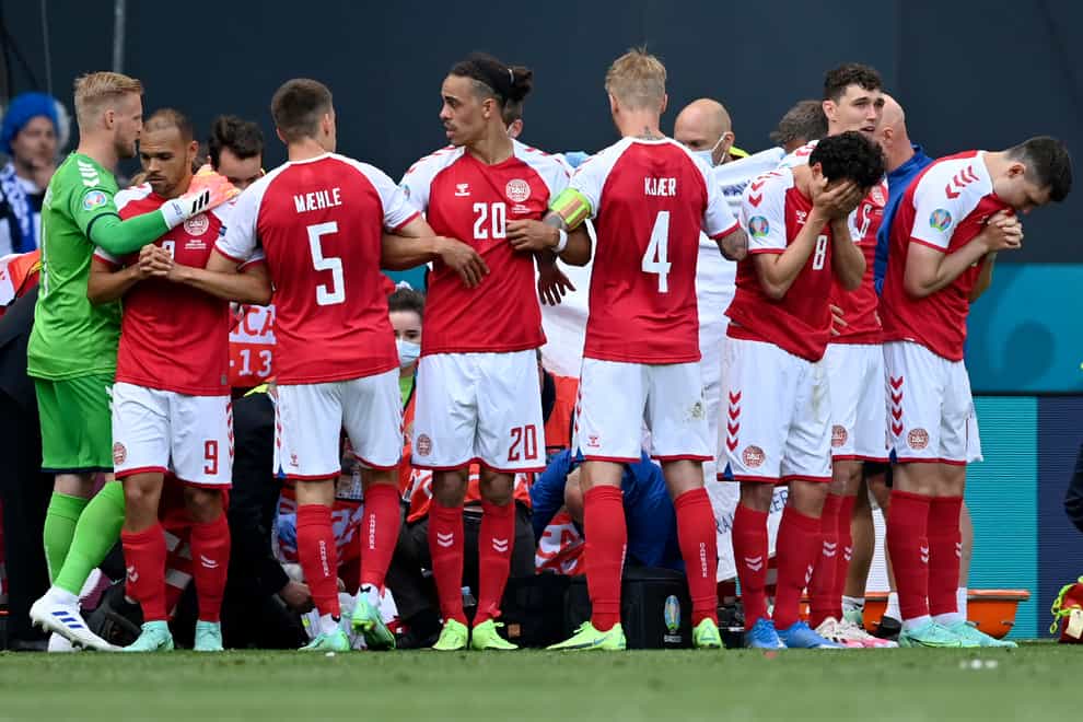 <p>Denmark players make a wall around team-mate Christian Eriksen as he receives treatment on the pitch</p>