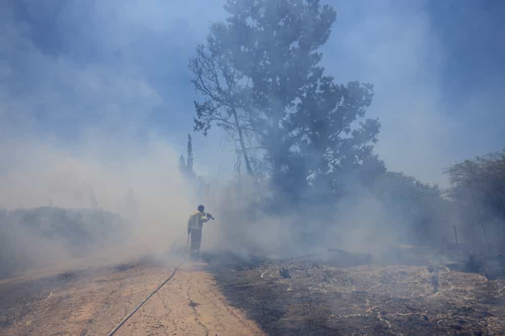 An Israeli firefighter attempts to extinguish a blaze caused by an incendiary balloon launched by Palestinians from the Gaza Strip
