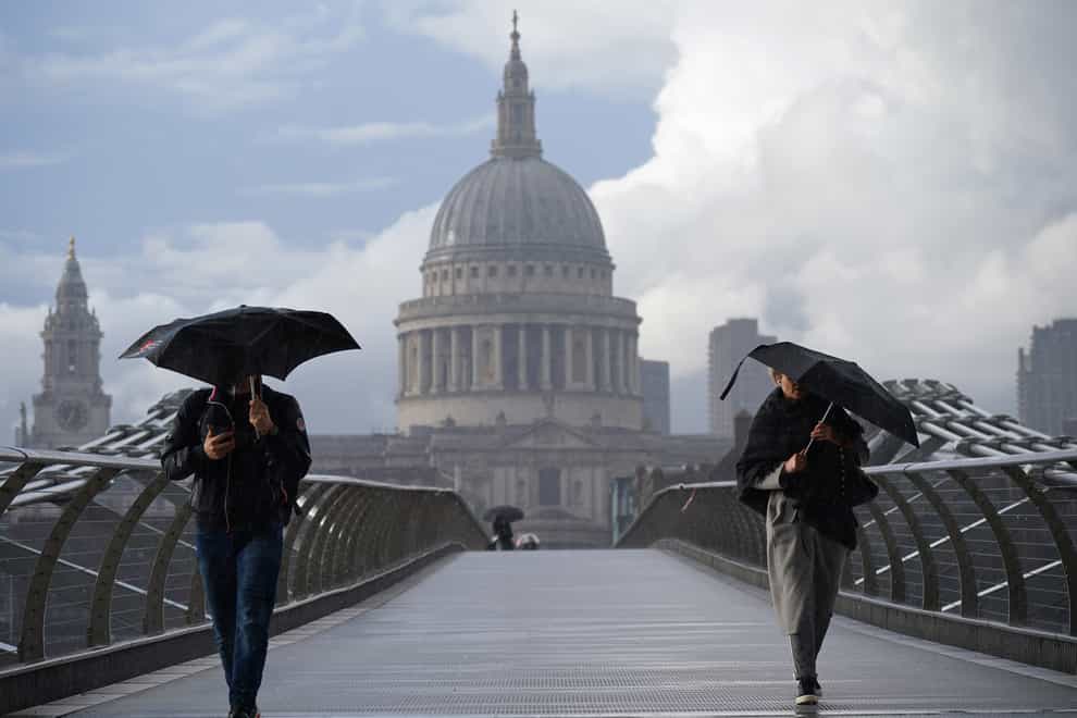 People cross London's Millennium Bridge in the rain