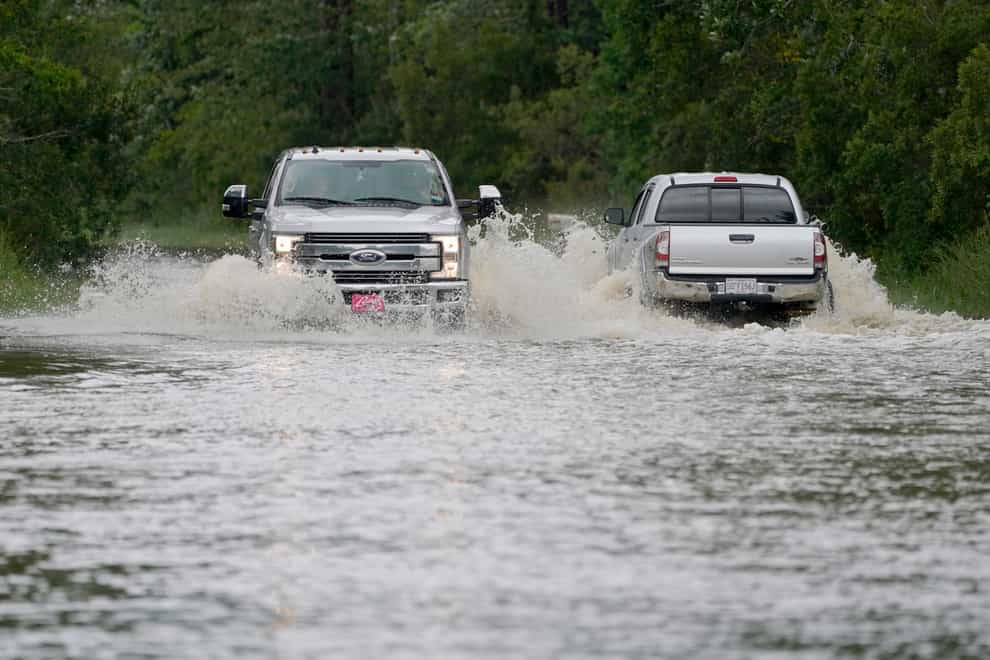 Pickup trucks pass each other on a flooded road in Biloxi, Mississippi