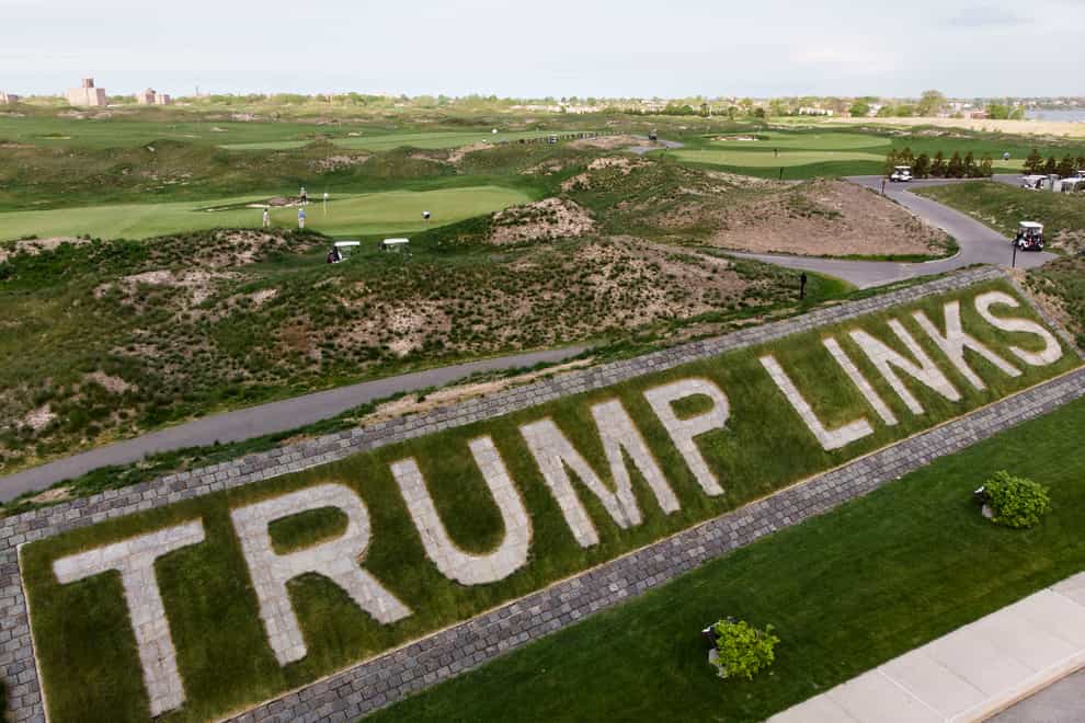 Patrons play golf near a giant branding sign at Trump Golf Links at Ferry Point in the Bronx