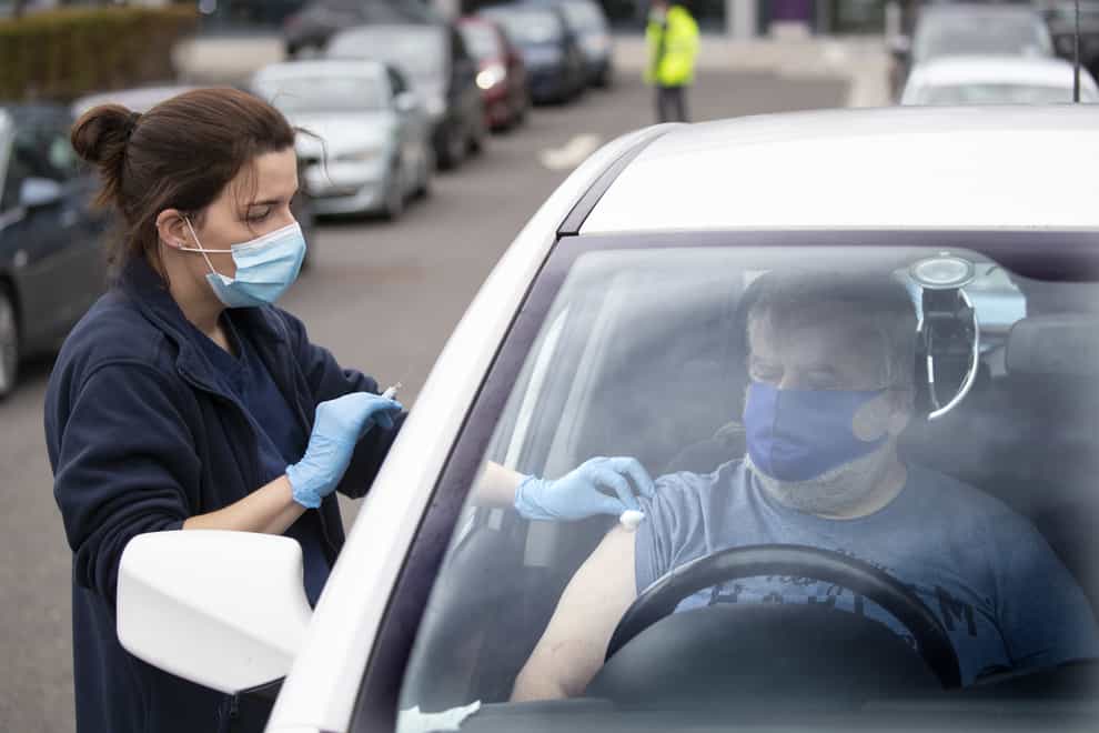 A member of the public receives a flu vaccine sat in their car at a drive-through clinic