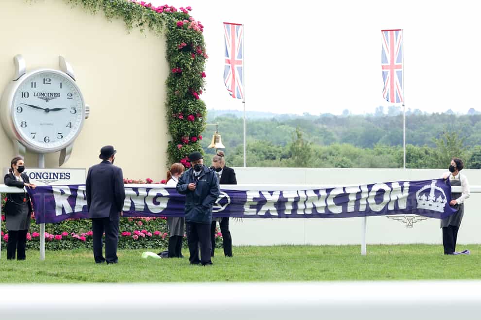 Protesters handcuff themselves to the railings and display a racing extinction banner during day five of Royal Ascot