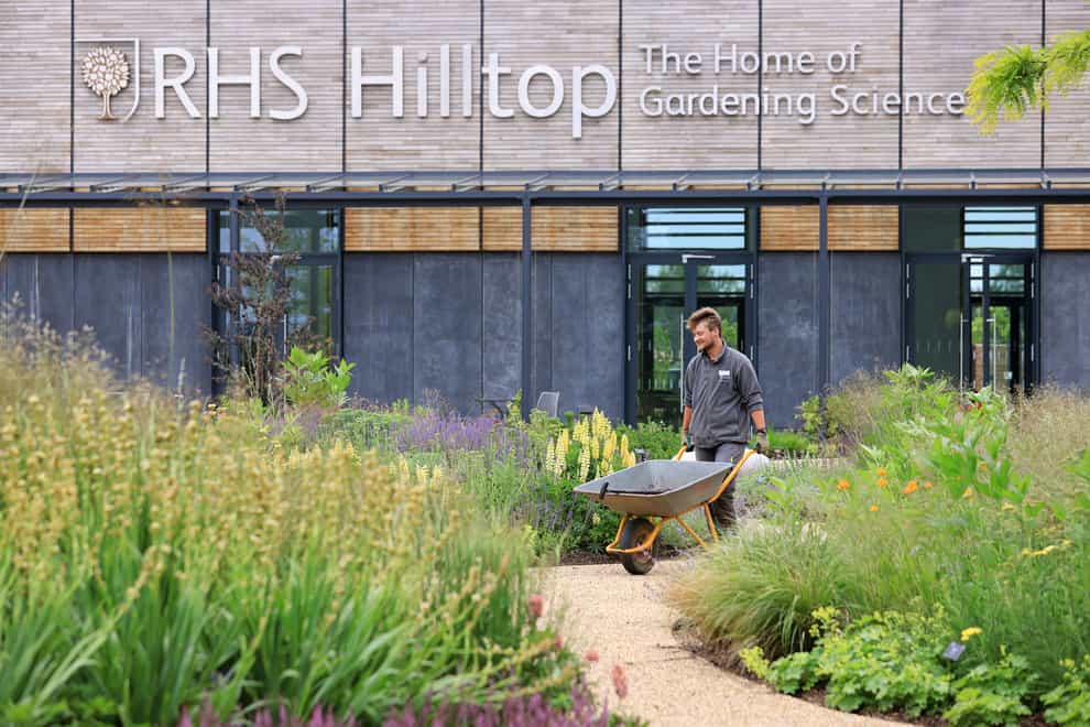 A gardener walks through the wellbeing garden in front of RHS Hilltop