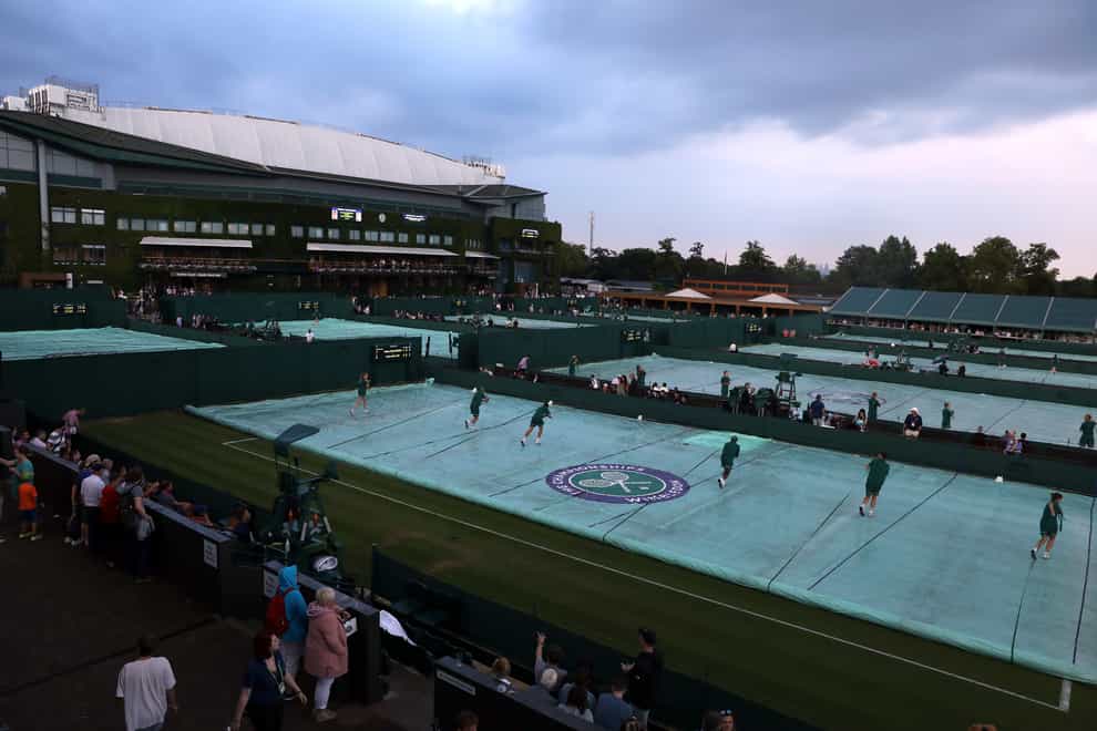 Ground staff removing covers on the outside courts at Wimbledon