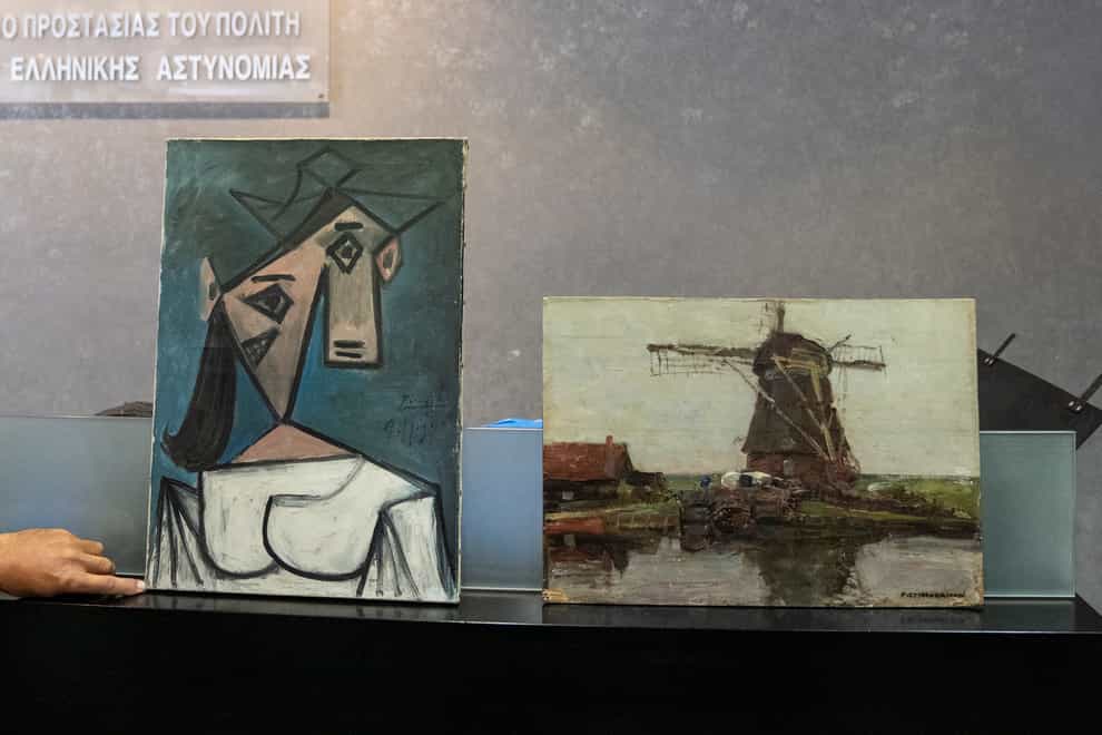 A cubist female bust by the Spanish painter Picasso, left, and a 1905 representational oil painting of a riverside windmill by the Dutch painter Mondrian are displayed by police officers, in Athens during a press conference (Petros Giannakouris/AP)