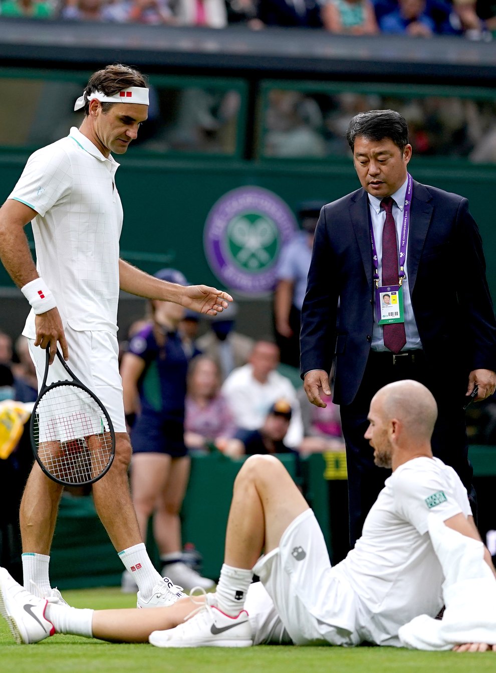 Roger Federer checks on Adrian Mannarino after his fall on Centre Court