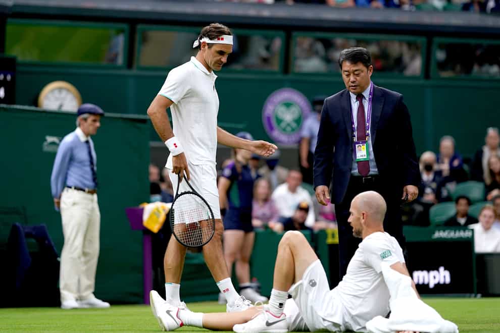 Roger Federer checks on Adrian Mannarino after his fall on Centre Court