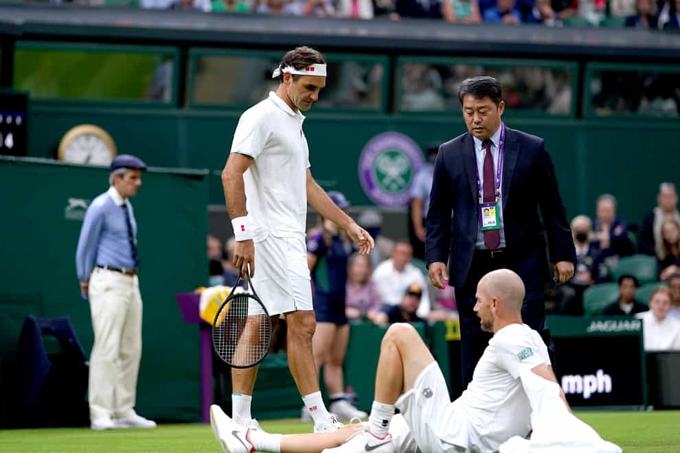 Roger Federer checks on Adrian Mannarino after his fall
