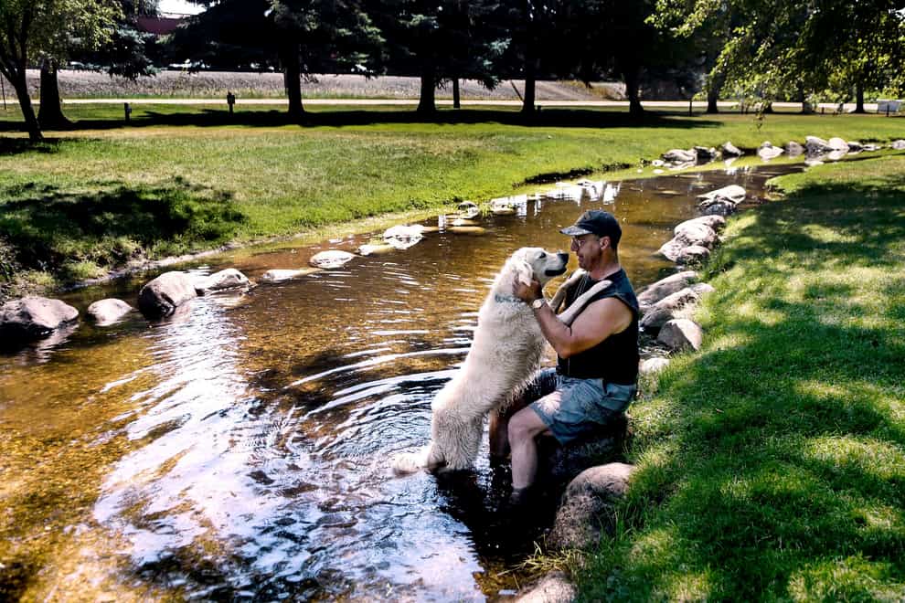 Robert Peluso of Blanchard and his dog Bailey cool off in the creek at Rathdrum’s City Park in Idaho