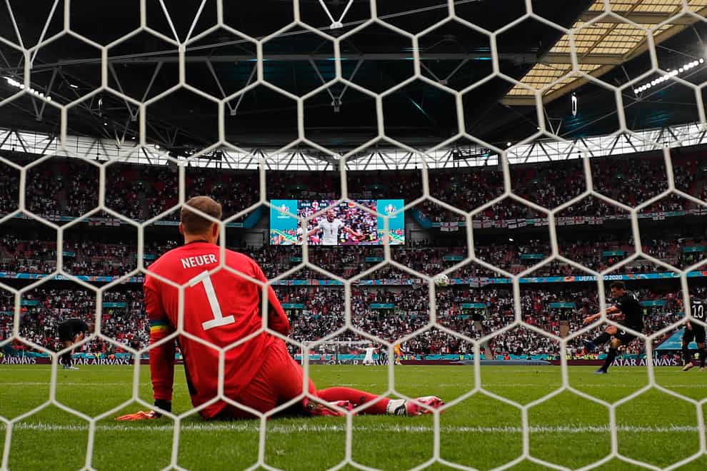 Germany goalkeeper Manuel Neuer sits on the ground while the video screen shows England’s Harry Kane celebrating