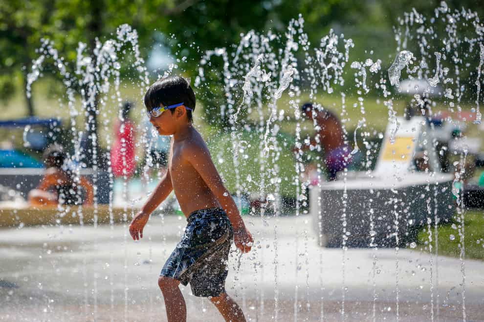 A young boy runs through a fountain at a splash park trying to beat the heat in Calgary, Alberta
