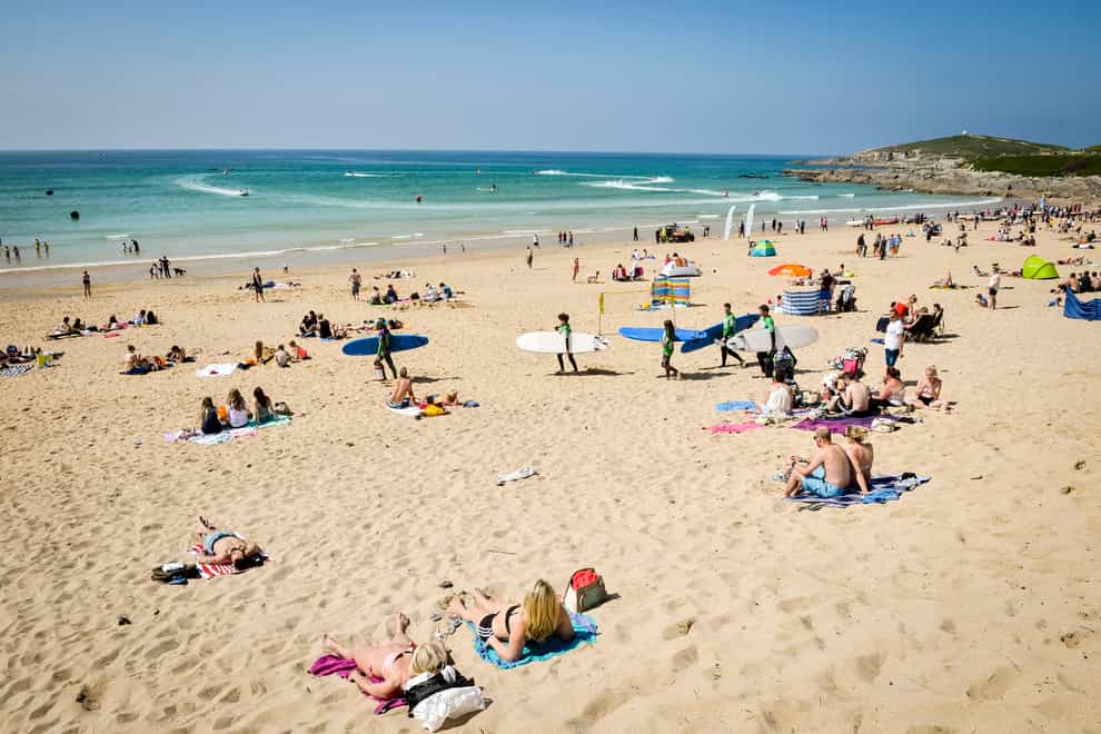 People relax in the sun at Fistral Beach