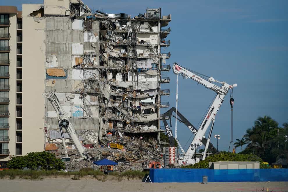Workers peer up at the rubble pile at the partially collapsed Champlain Towers South apartment building in Surfside, Florida