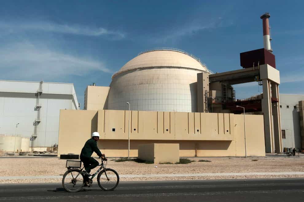 A worker rides a bicycle in front of the reactor building of the Bushehr nuclear power plant (Majid Asgaripour/AP)