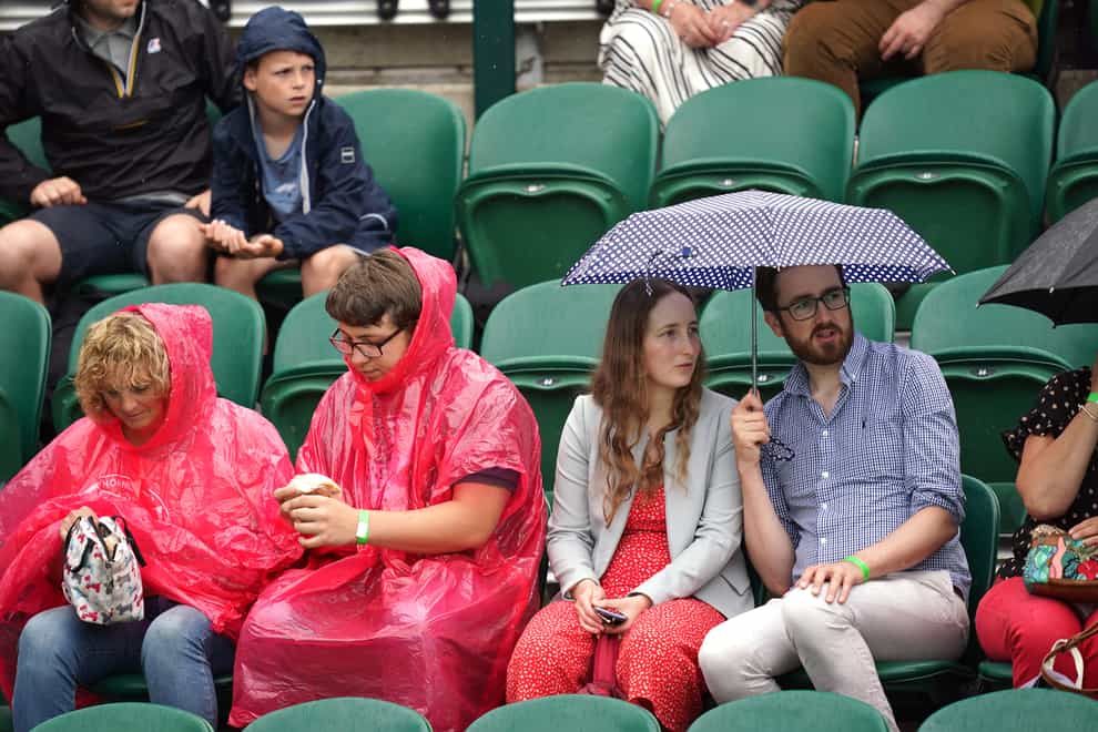 <p>Spectators shelter from the rain on day six of Wimbledon</p>