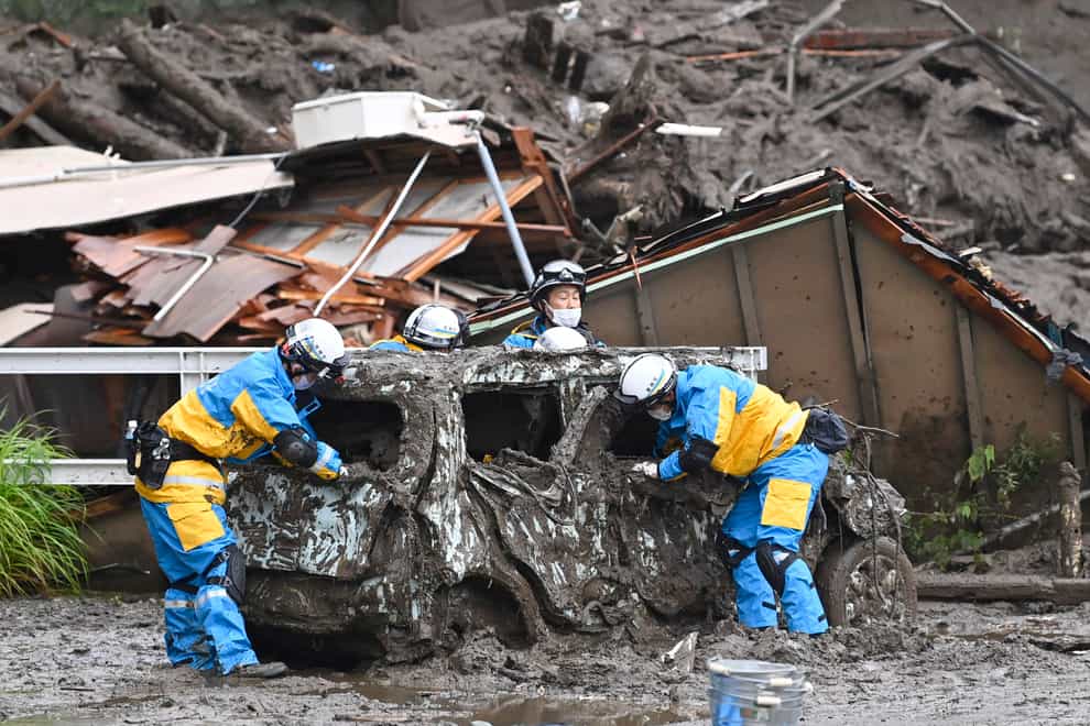 Rescuers check a damaged vehicle at the site of a mudslide in Atami, Shizuoka prefecture, southwest of Tokyo