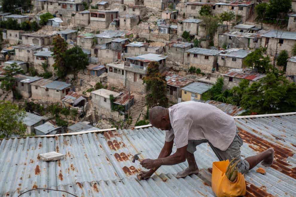 Antony Exilien secures the roof of his house in response to Tropical Storm Elsa in Port-au-Prince, Haiti
