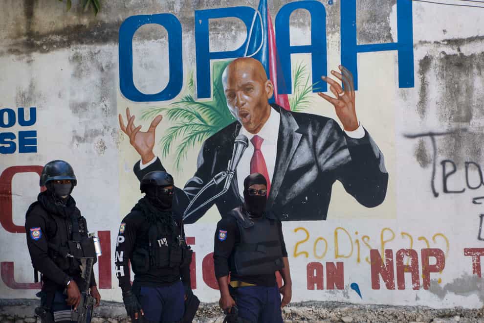 Police stand near a mural featuring Haitian President Jovenel Moise, near the leader’s residence where he was killed by gunmen