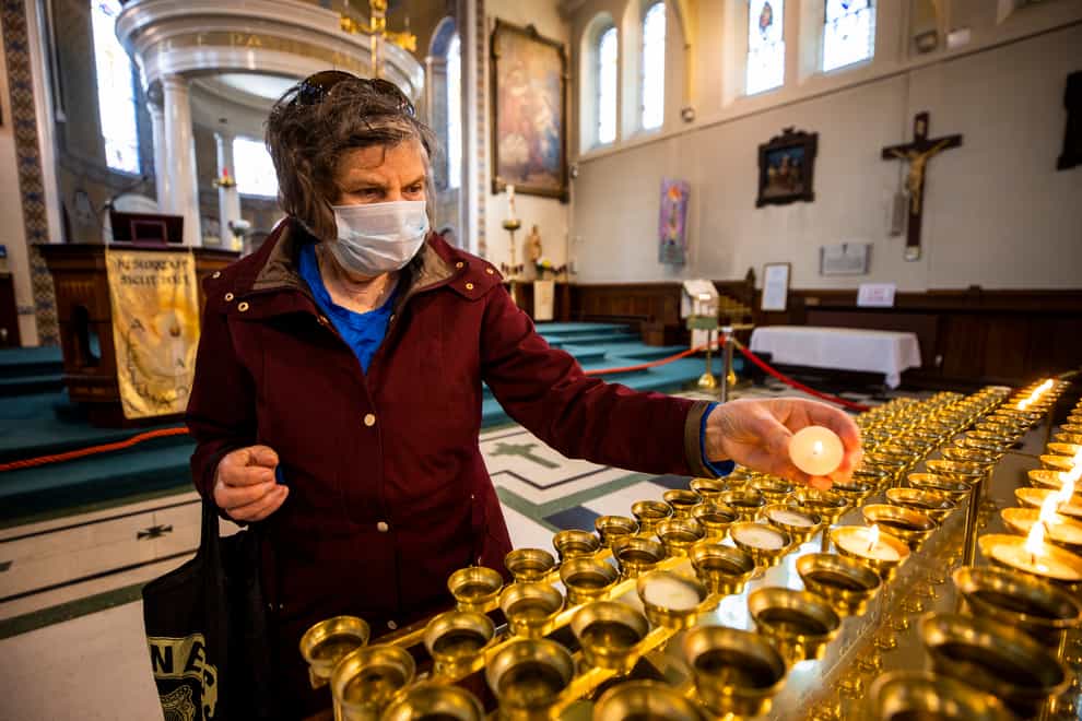 A woman lights a candle in St Mary's Church in Belfast