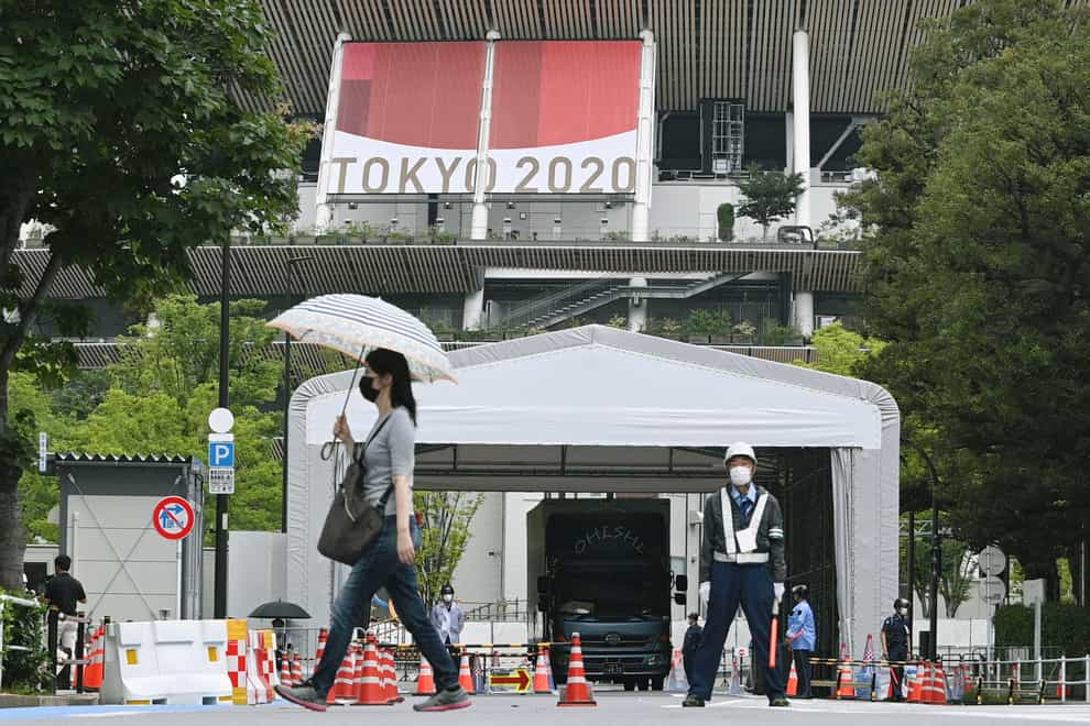 People wearing face masks walk past the National Stadium in Tokyo