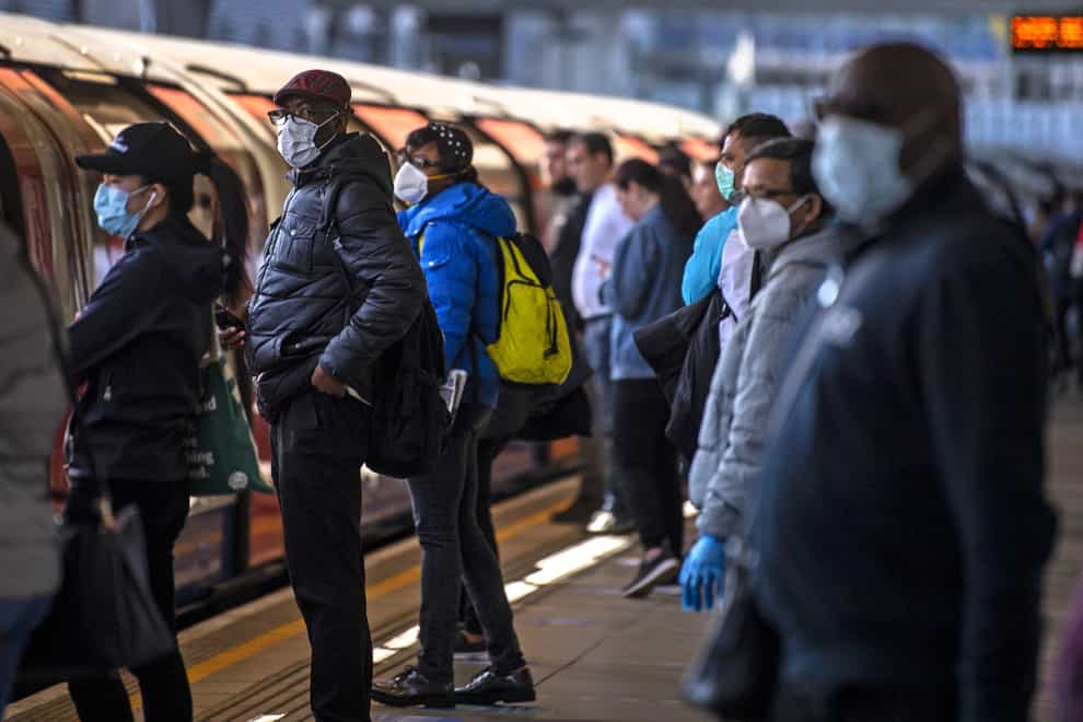 Tube passengers on a station platform wearing face masks