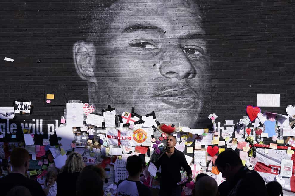 People gather to view the messages of support at a mural of England player Marcus Rashford in Manchester