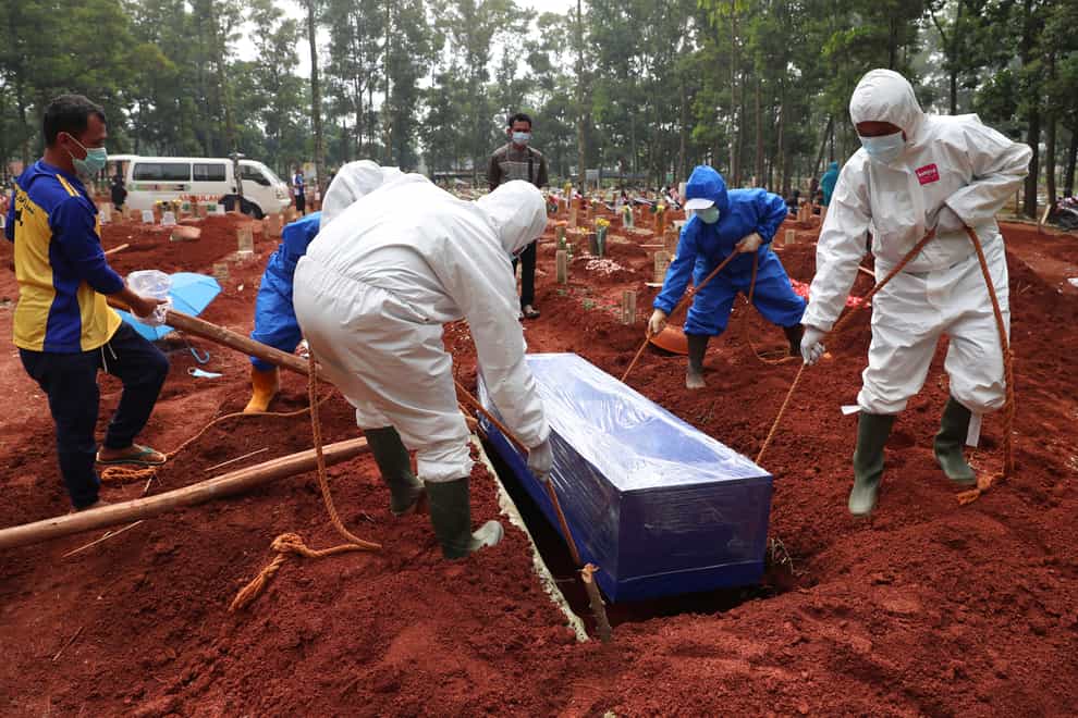 Workers in protective gear lower the coffin of a Covid-19 victim into a grave at the Cipenjo Cemetery in Bogor, Indonesia