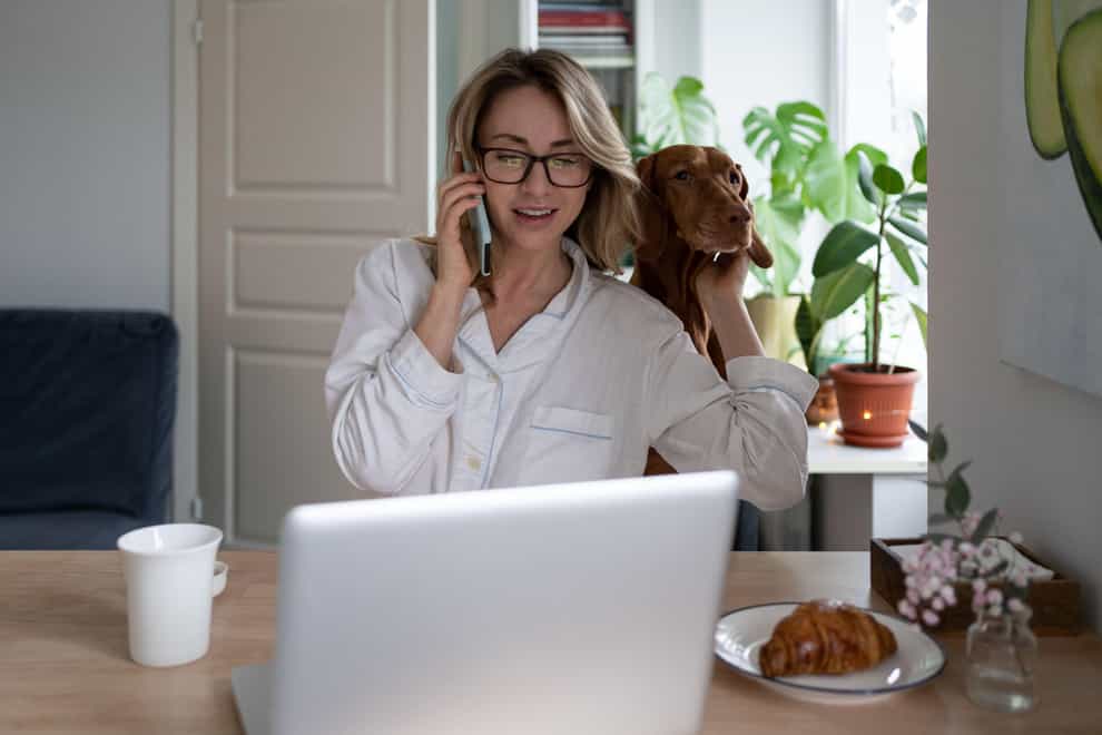Woman working from home, talking on mobile, hugging her dog