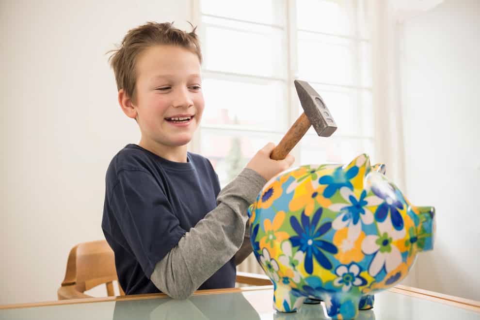 Smiling boy with piggy bank and hammer