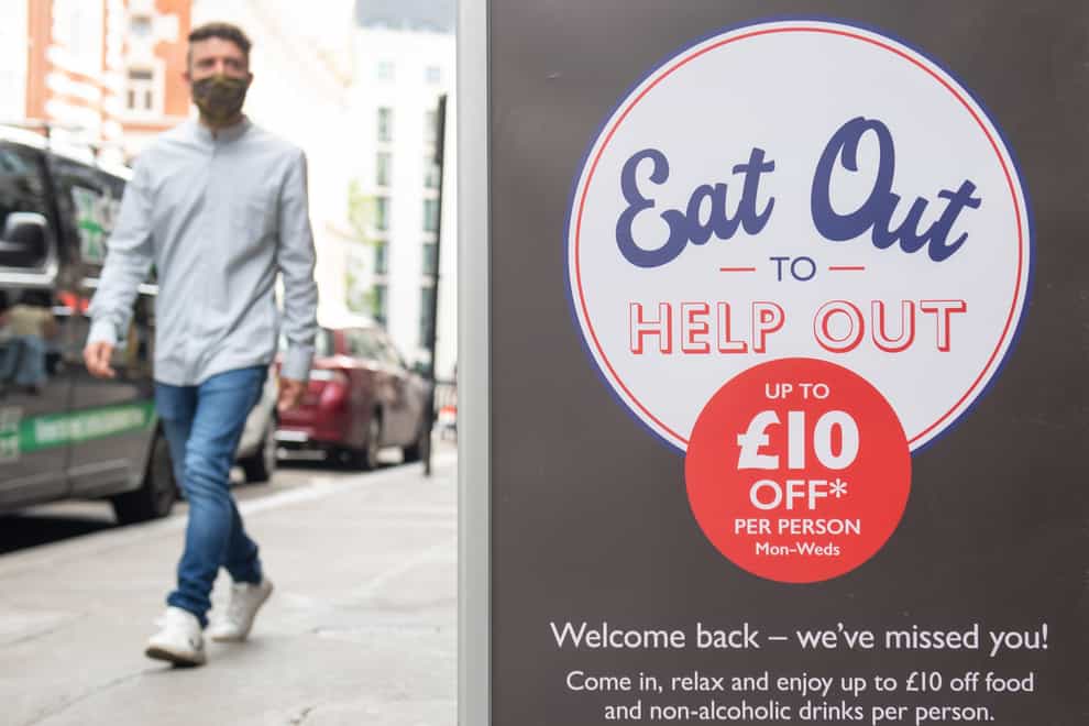 People pass a sign advertising the Eat Out to Help Out scheme last summer