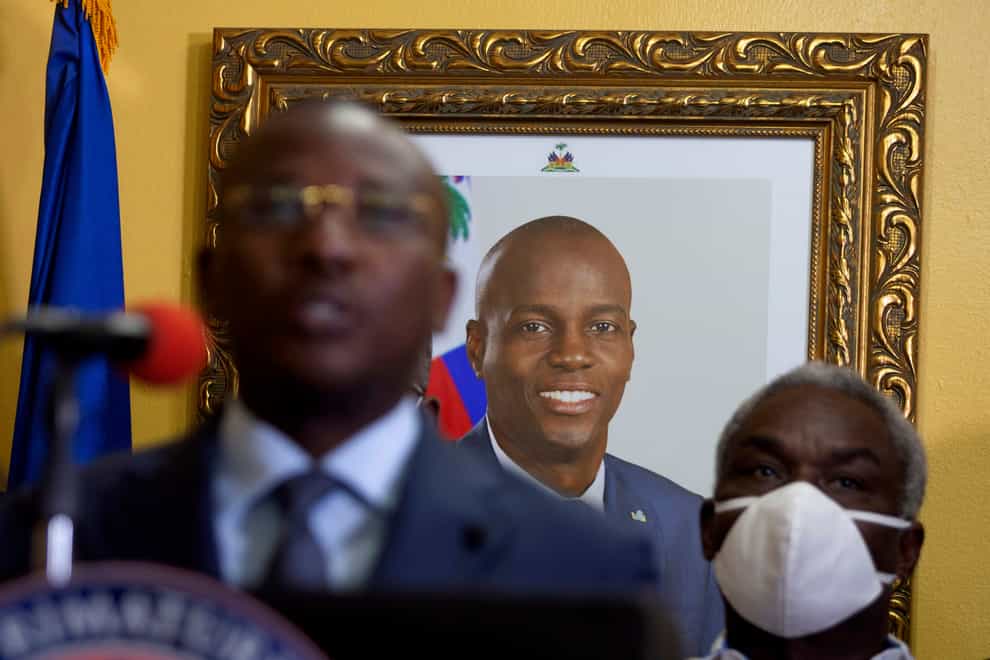 A picture of late Haitian President Jovenel Moise hangs on the wall of his former residence, behind interim prime minister Claude Joseph (Joseph Odelyn/AP)