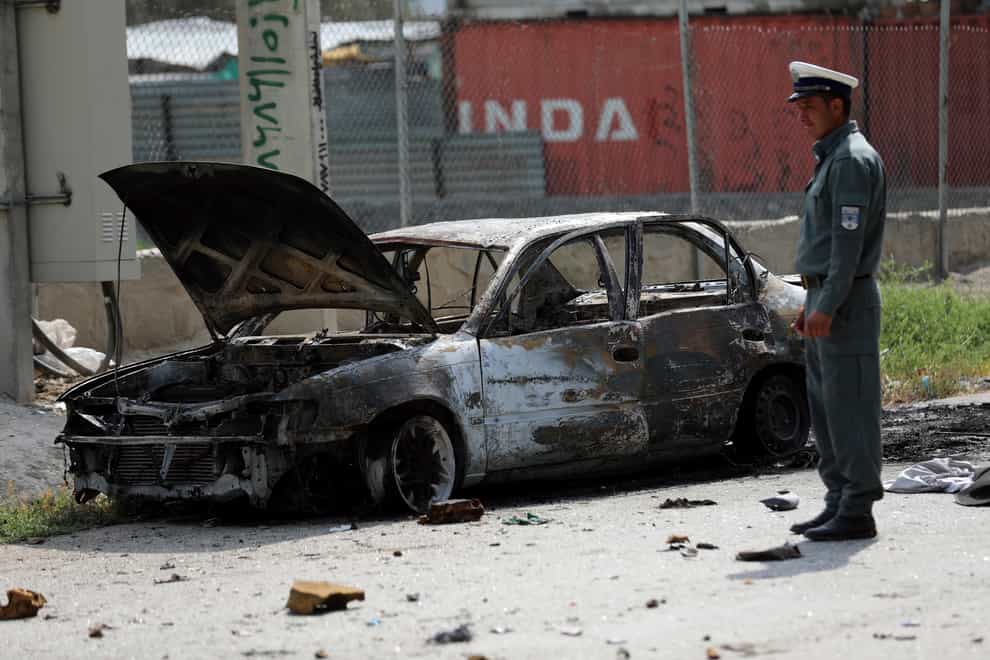 Afghan traffic police stand near a damaged vehicle where rockets were fired from in Kabul, Afghanistan (Rahmat Gul/AP)
