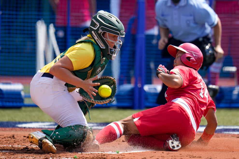 A Japan player slides onto base as an Australia player catches the softball