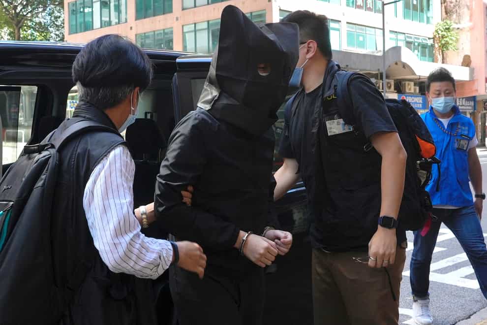A hooded suspect is accompanied by police officers to searchfor evidence at an office in Hong Kong (Vincent Yu/AP)