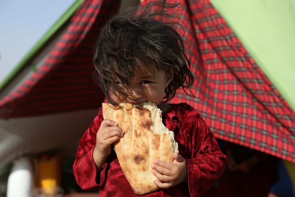 An internally displaced Afghan girl whose family fled their home due to fighting between the Taliban and Afghan security personnel, eats bread (Rahmat Gul/AP)