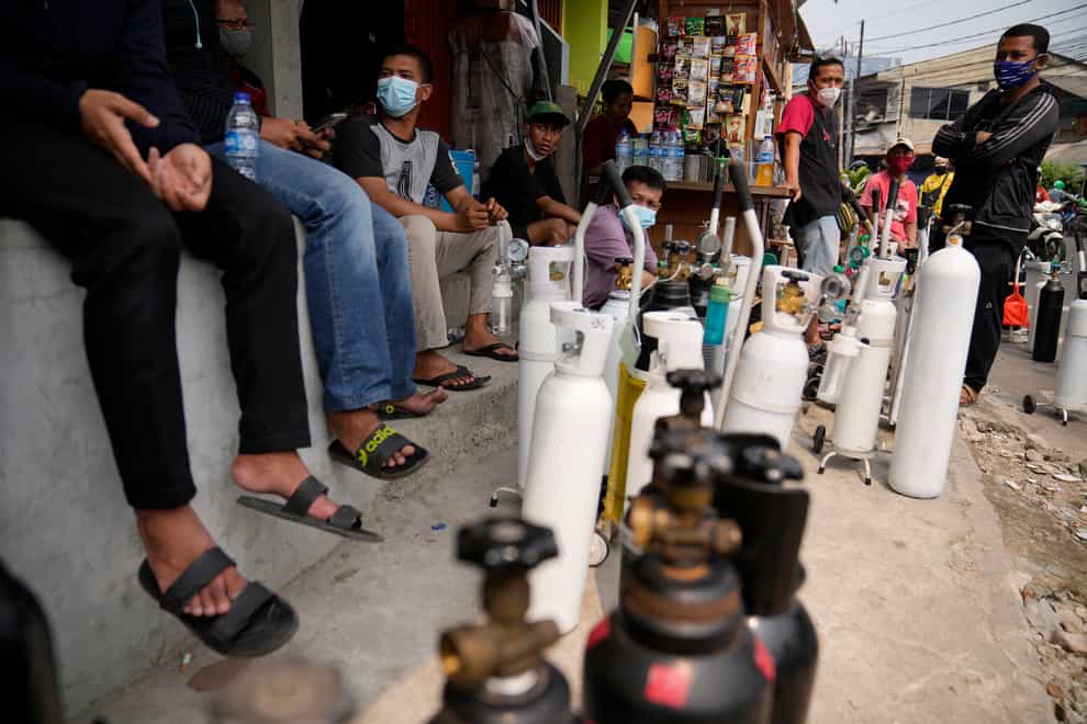 People queue up to refill their oxygen tanks at a filling station in Jakarta, Indonesia (Dita Alangkara/AP)