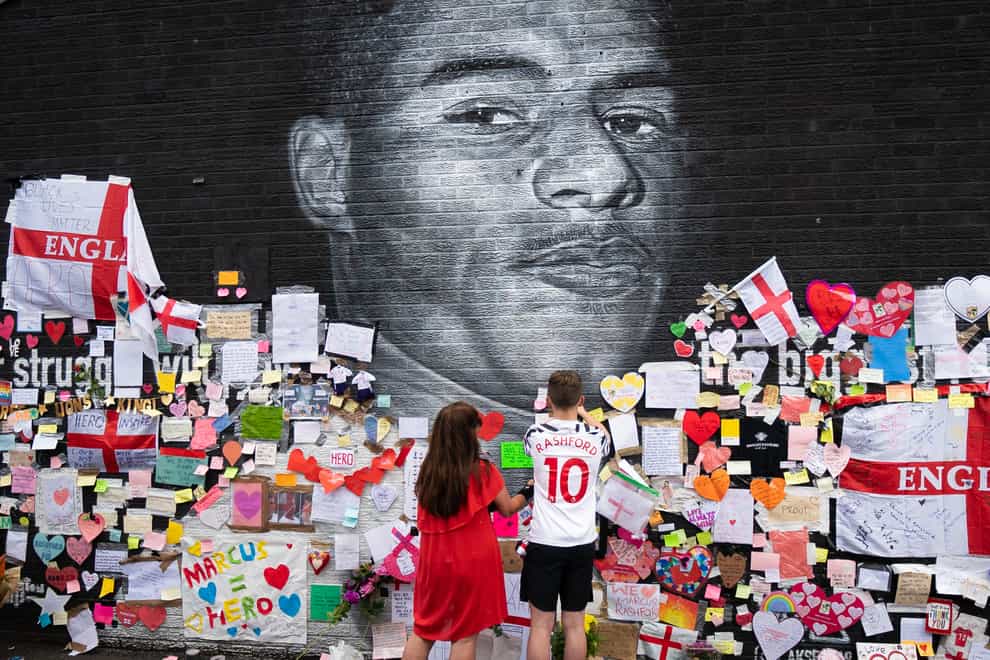 Mackenzie Robertson and his mother Sally Coles-Robertson put up a message on the mural of Manchester United striker and England player Marcus Rashford in Withington (Danny Lawson/PA)