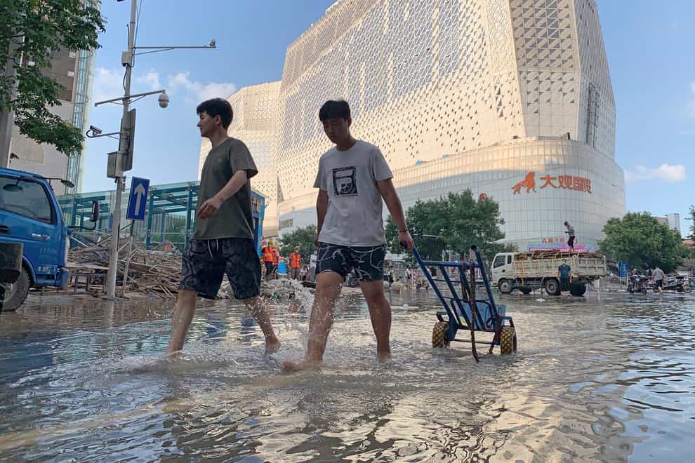 Residents walk along a flooded road in the aftermath of the heaviest recorded rainfall in Zhengzhou (Dake Kang/AP/PA)