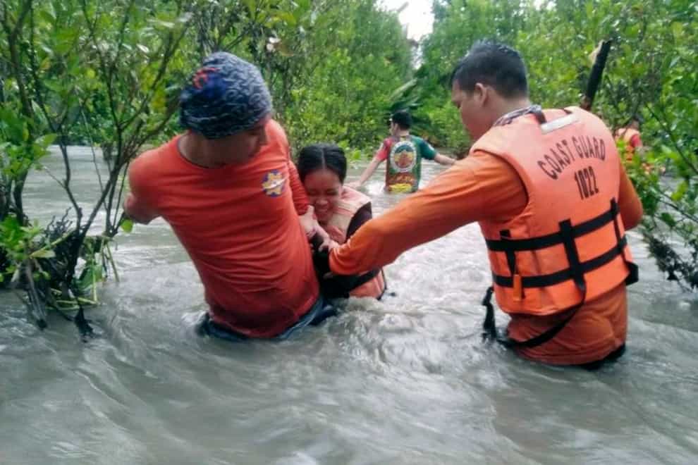Residents wade through floodwaters as they are evacuated in Naujan, Oriental Mindoro province (Philippine Coast Guard/AP)
