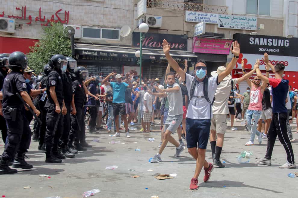 Protesters face Tunisian police officers during a demonstration in Tunis (Hassene Dridi/AP)