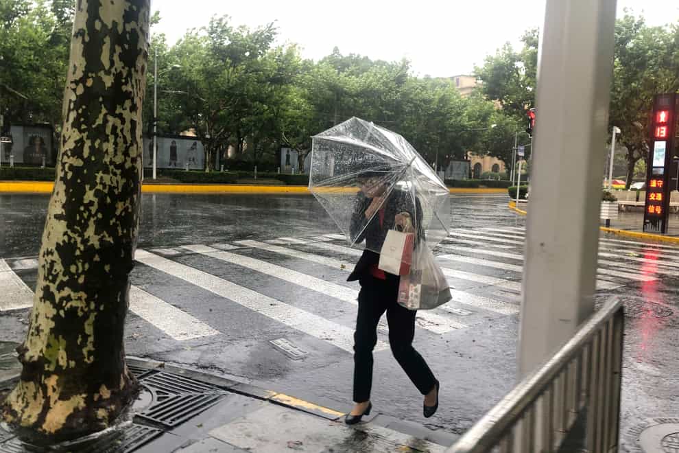 A woman carrying an umbrella braces against the wind and rain as Typhoon In-fa sweeps through Shanghai (AP)
