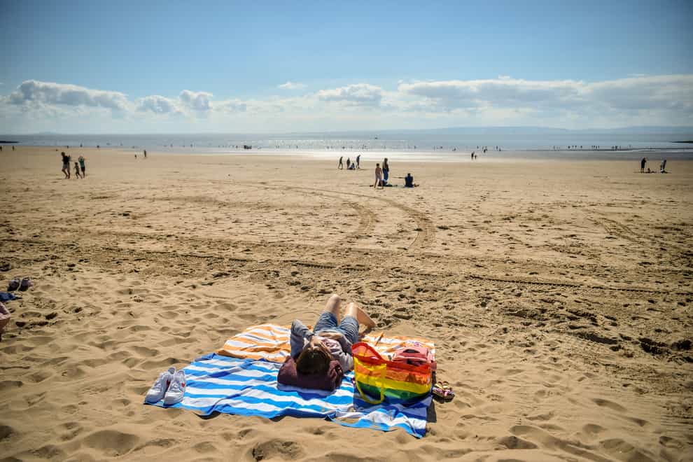 People sunbathing on the beach (PA)