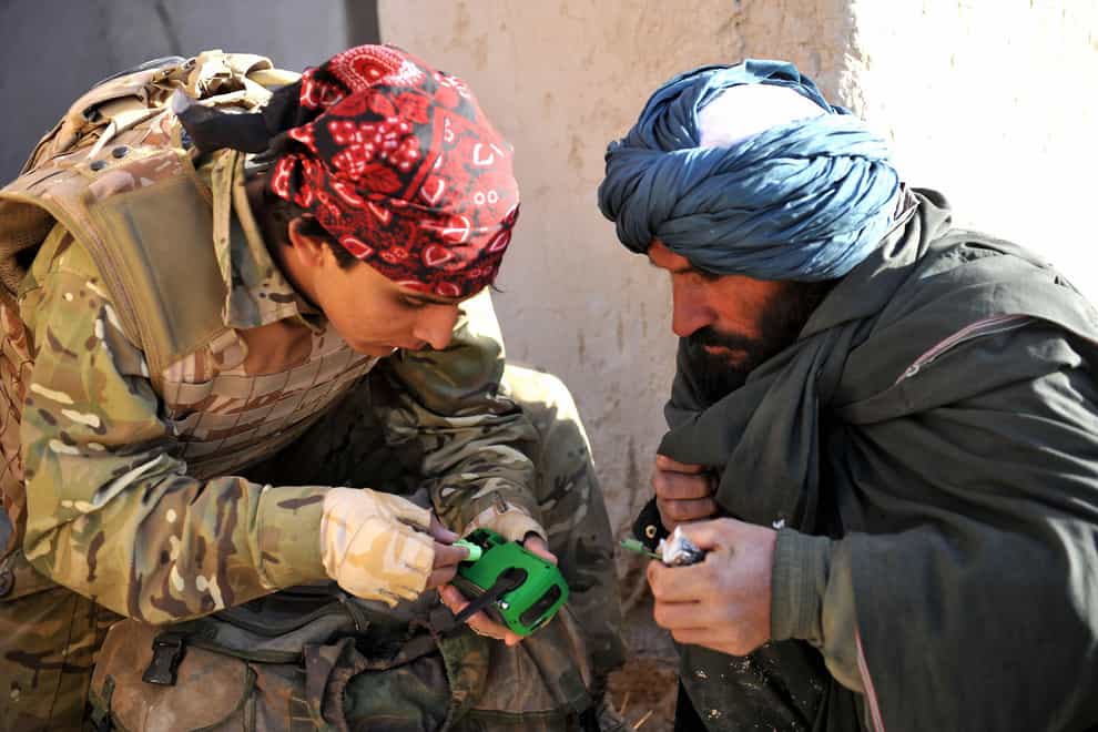 Ministry of Defence undated handout photo of an interpreter working for ISAF, gives a local man a wind up radio, supplied by ISAF as he takes part in Operation Zamary Kargha. An air insertion operation has been mounted by British soldiers and Afghan police, re-establishing government control in an area of Helmand province previously under heavy Taliban influence.