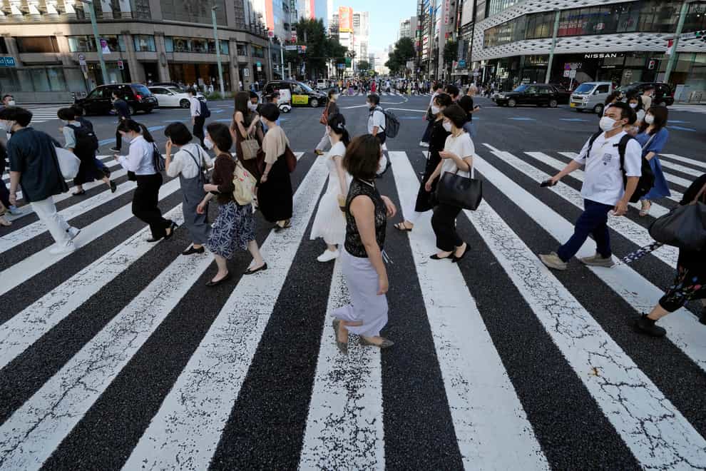 People in Tokyo wearing protective masks to help curb the spread of the virus (Eugene Hoshiko/AP)