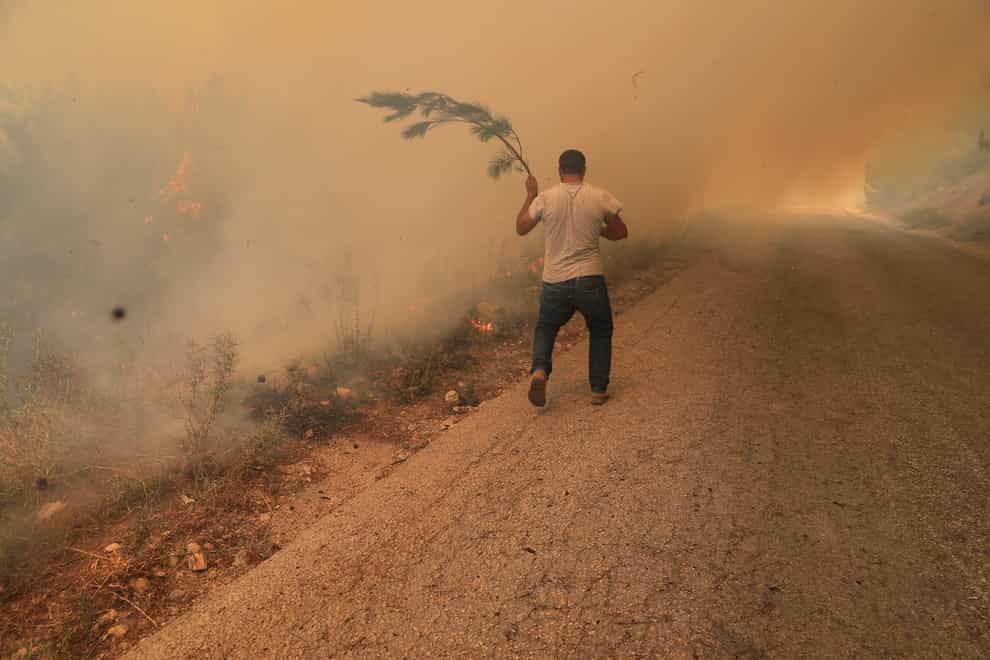 A man runs to extinguish a forest fire, at Qobayat village, in the northern Akkar province, Lebanon (Hussein Malla/AP)